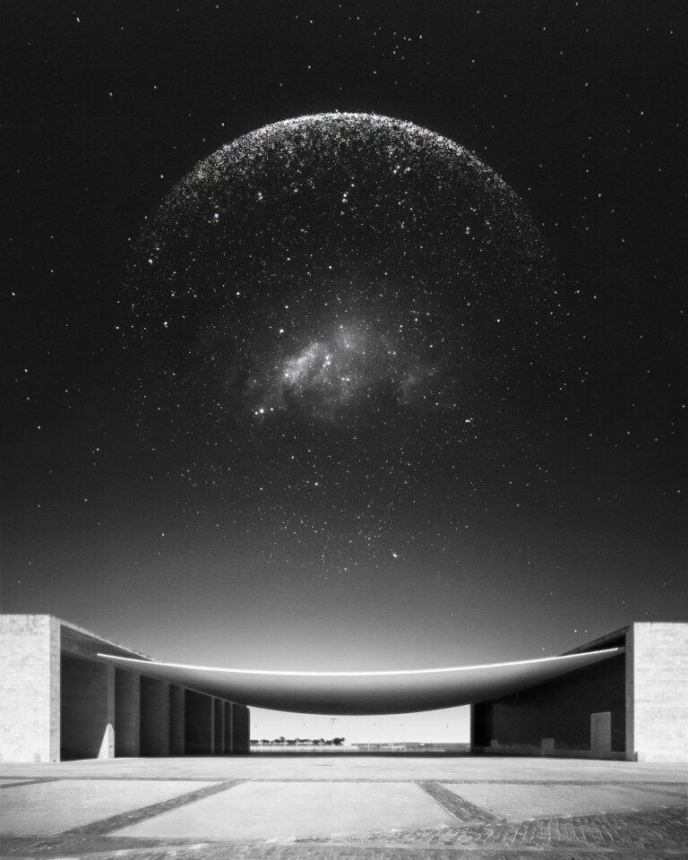 The Pavilhão de Portugal by Álvaro Siza Vieira with a luminous sphere of light points resembling a celestial atlas hovering above the building’s curved canopy.